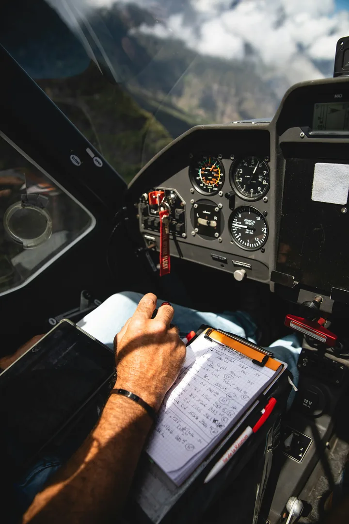 A pilot's hand writing on a kneeboard in a light aircraft's cockpit