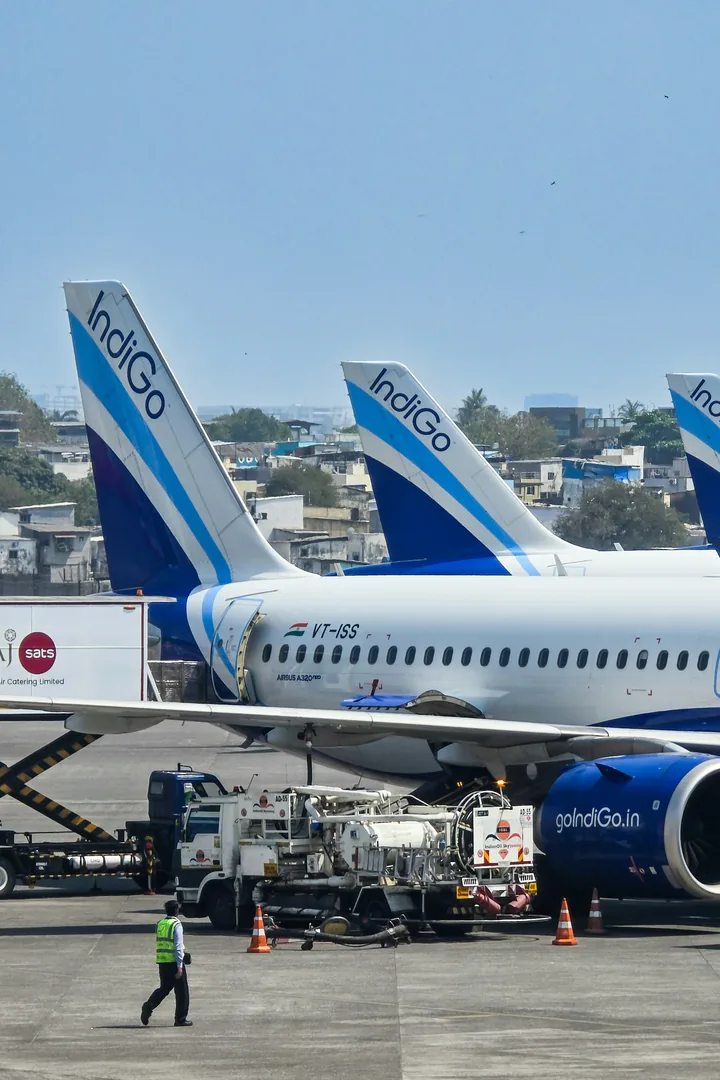 IndiGo A320s on the apron, a ground crew walking past