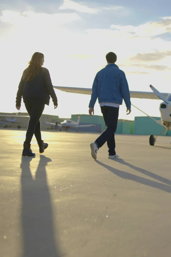 Two student pilots walking out to a light aircraft at sunrise