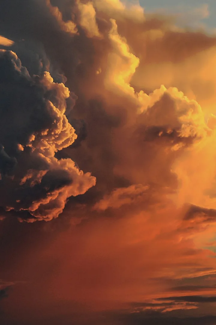 A towering cloud lit orange by the sunset